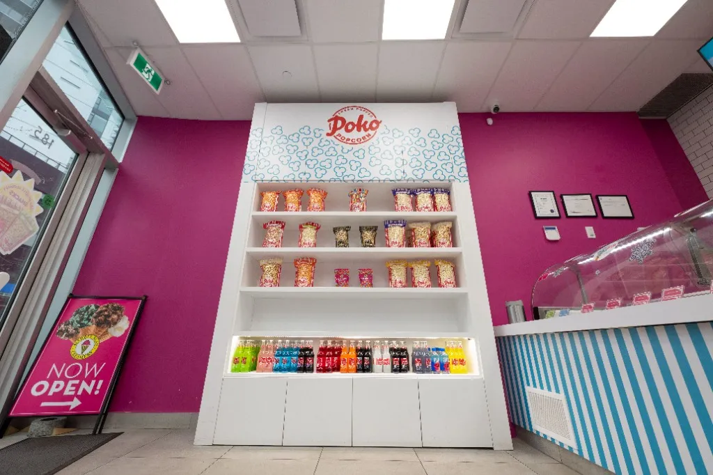 Product display shelves against a pink feature wall beside the service counter — MARBLE SLAB CREAMERY — SURREY, BC