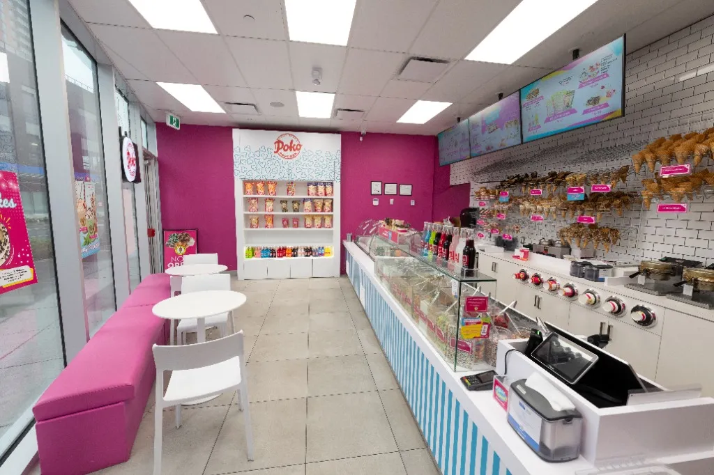 Retail interior with pink bench seating, white tables and a striped display counter — POKO POPCORN — SURREY, BC