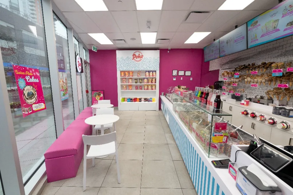 Pink upholstered bench and white tables opposite a glass retail display counter — MARBLE SLAB CREAMERY — SURREY, BC