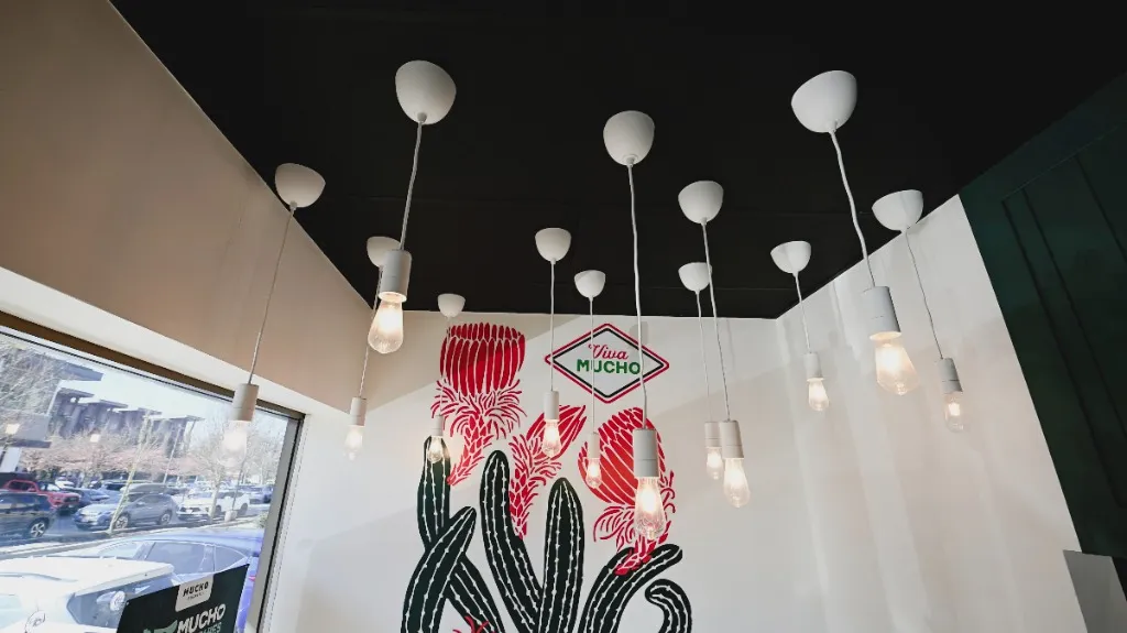 Cluster of pendant lights above a floral mural and restaurant seating — MUCHO BURRITO — SURREY, BC